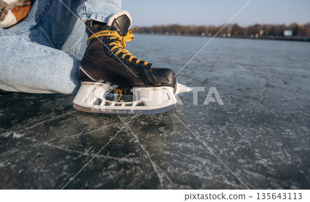 Getting ready, wearing skates. A man is on the ice in winter Getting ready, wearing skates. A man is on the ice in winter 135643113