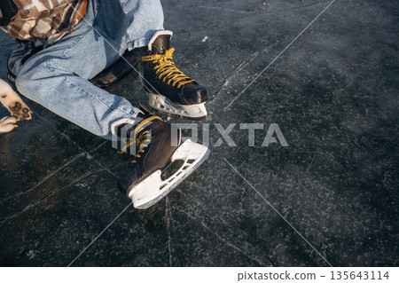 Getting ready, wearing skates. A man is on the ice in winter 135643114