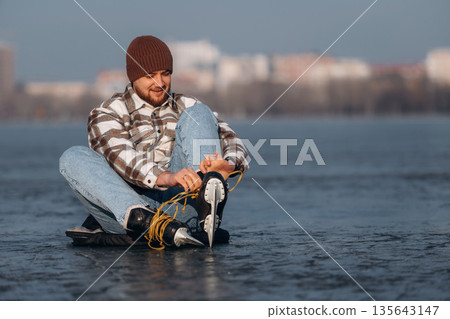 Getting ready, wearing skates. A man is on the ice in winter 135643147