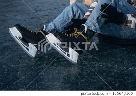 Sitting on the ice. Close up view of man that is with skates in winter 135643160