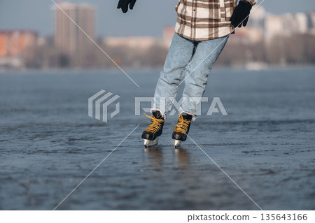 Daytime leisure activity. Close up view of man that is on ice with skates in winter Daytime leisure activity. Close up view of man that is on ice with skates in winter 135643166