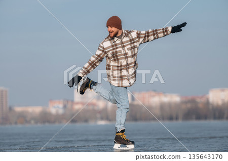 Having fun by riding. A man is on the ice with his skates in winter Having fun by riding. A man is on the ice with his skates in winter 135643170