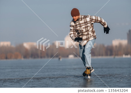 In motion, riding. A man is on the ice with his skates in winter In motion, riding. A man is on the ice with his skates in winter 135643204