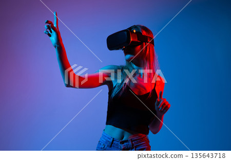 Female User Exploring Virtual Reality With Hand Gesture Control, Futuristic VR Experience and Advanced Digital Technology Concept 135643718