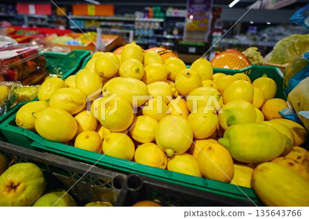 Lemons are piled high in a green basket at a grocery store 135643766