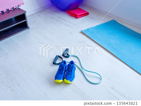 Sports shoes and resistance band on gym floor 135643821