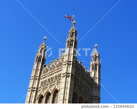Westminster Abbey tower and British flag against a blue sky Westminster Abbey tower and British flag against a blue sky 135644020