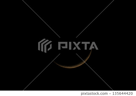 A thin moon floating in the night sky 135644420