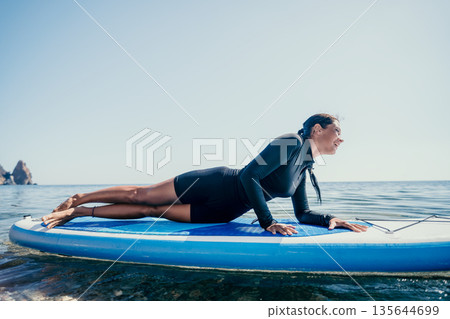 Woman Paddleboard Yoga Ocean - Female doing yoga on paddleboard in ocean. 135644699