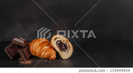 Chocolate filled croissant with dark chocolate pieces on black background with copy space Chocolate filled croissant with dark chocolate pieces on black background with copy space 135644939
