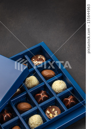 Luxury assorted chocolate pralines in blue gift box on dark background Luxury assorted chocolate pralines in blue gift box on dark background 135644963