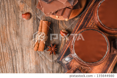 Hot chocolate drinks with cinnamon and chocolate on wooden table Hot chocolate drinks with cinnamon and chocolate on wooden table 135644980