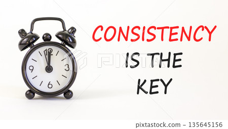 Consistency is the key symbol. Concept words Consistency is the key on beautiful white paper. Beautiful white paper background. Black alarm clock. Business consistency is the key concept. Copy space. 135645156
