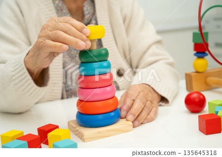 Asian elderly woman playing enhancing skill board game. Asian elderly woman playing enhancing skill board game. 135645318