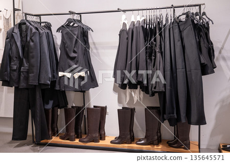 Black fashion display with dresses, coats, and boots on rack Black fashion display with dresses, coats, and boots on rack 135645571