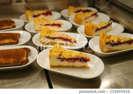 Sliced cheesecake with berry topping on plates in a restaurant setting 135645626
