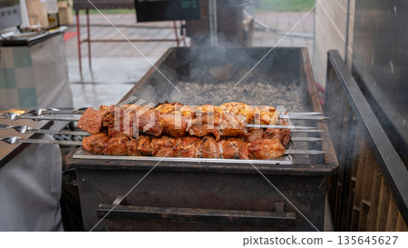 Grilled shashlik skewers on outdoor charcoal grill in street food market 135645627