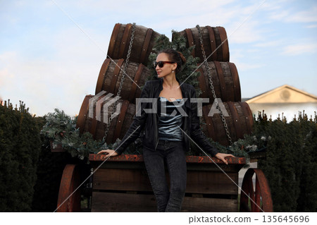 Girl in sunglasses and leather jacket with barrels Girl in sunglasses and leather jacket with barrels 135645696