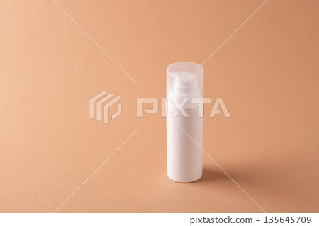 Minimal cosmetic bottle with copy space on beige background Minimal cosmetic bottle with copy space on beige background 135645709
