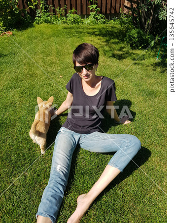 Happy Woman Holding Corgi Puppy in Sunny Garden Happy Woman Holding Corgi Puppy in Sunny Garden 135645742