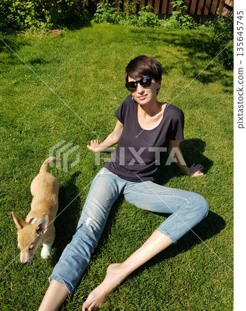 Happy Woman Holding Corgi Puppy in Sunny Garden Happy Woman Holding Corgi Puppy in Sunny Garden 135645745