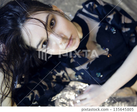 Attractive woman in stylish top posing on silver Attractive woman in stylish top posing on silver 135645805