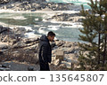 Young Man by Icy Turquoise River in Winter Landscape 135645807