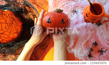 Handmade pumpkin painting on an orange background with a spider web Handmade pumpkin painting on an orange background with a spider web 135645970