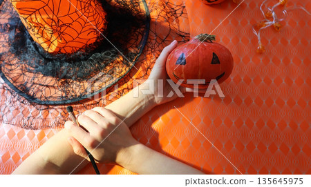 Handmade pumpkin painting on an orange background with a spider web Handmade pumpkin painting on an orange background with a spider web 135645975