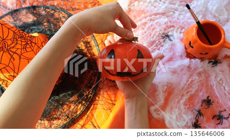 Handmade pumpkin painting on an orange background with a spider web  135646006