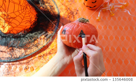 Handmade pumpkin painting on an orange background with a spider web Handmade pumpkin painting on an orange background with a spider web 135646008