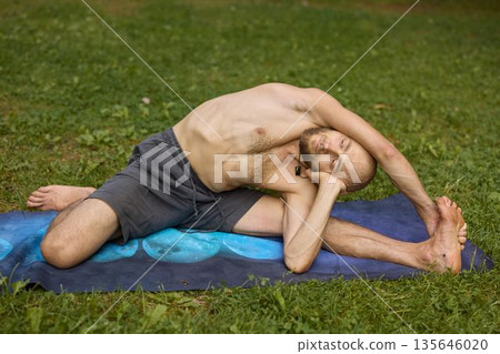Individual practicing deep side bends on mat during outdoor workout session Individual practicing deep side bends on mat during outdoor workout session 135646020