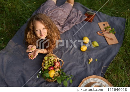 Gentle lady reclining on cloth sharing moment with apples and sunshine Gentle lady reclining on cloth sharing moment with apples and sunshine 135646038