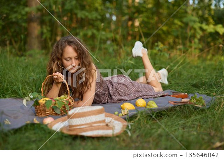 Calm female enjoying natural life during restful picnic in meadow Calm female enjoying natural life during restful picnic in meadow 135646042