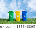 Colorful recycling bin on grass over sky background. Containers for waste separation, promoting eco friendly living and environmental awareness. Waste management, clean environment concept. 135646895