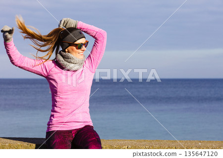 Woman resting after doing sports outdoors on cold day 135647120