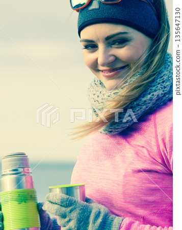 Fit woman in cold day warming up drink tea 135647130