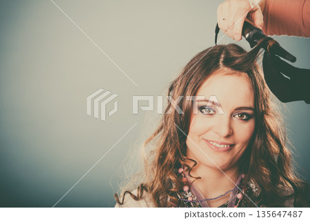 Hairdresser curling woman hair with iron curler. Hairdresser curling woman hair with iron curler. 135647487