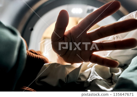 Hand reaching into washing machine for laundry 135647671