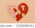 Broken heart shape crafted from red and pink paper piece arranged on beige background representing relationship breakup and heartbreak emotion for valentine day 135648161
