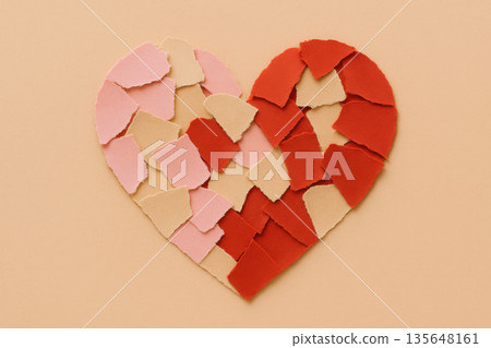 Broken heart shape crafted from red and pink paper piece arranged on beige background representing relationship breakup and heartbreak emotion for valentine day Broken heart shape crafted from red and pink paper piece arranged on beige background representing relationship breakup and heartbreak emotion for valentine day 135648161