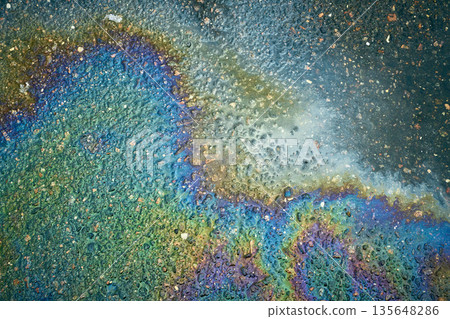 Colorful Patterns Form on Wet Pavement After Rain Following an Oil Spill in an Urban Area During Daylight Hours 135648286