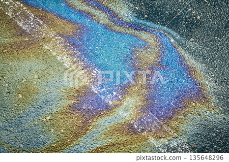 Gasoline puddle showing colorful iridescent reflections on dark asphalt texture 135648296