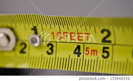Macro view of a metal retractable tape measure showing feet and metric increments Macro view of a metal retractable tape measure showing feet and metric increments 135648358