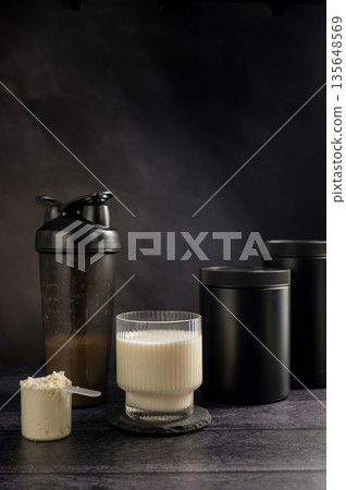 Protein drink in a glass with protein shaker and tube on dark background. Body building, muscle growth and food supplement concept 135648569