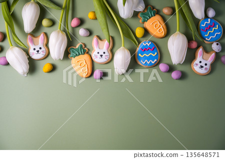 Easter spring holiday background with easter cookies: buny, carrot and egg with white tulip flowers, flat lay 135648571