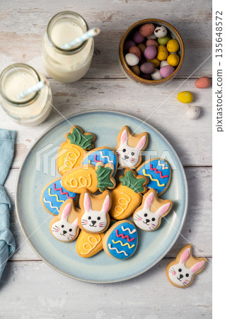 Easter cookies with bottles of milk on white wooden background and mini chocolate easter candy eggs. Spring holidays background Easter cookies with bottles of milk on white wooden background and mini chocolate easter candy eggs. Spring holidays background 135648572