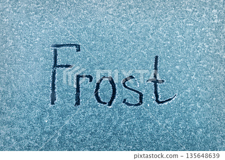 Frost Written in White on a Blue Background, Showcasing the Beauty of Winter's Touch on Surfaces Frost Written in White on a Blue Background, Showcasing the Beauty of Winter's Touch on Surfaces 135648639