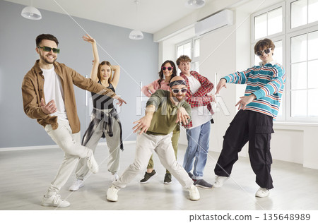 Happy group of young people dancers dancing together during dance class in modern studio. Happy group of young people dancers dancing together during dance class in modern studio. 135648989