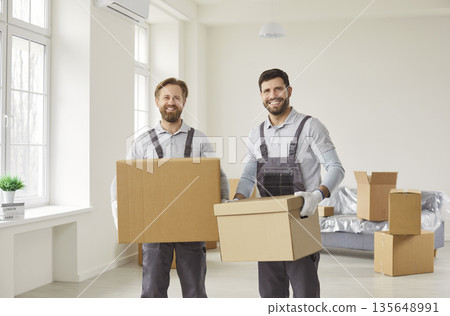 Professional movers carrying cardboard boxes during home relocation and delivery 135648991